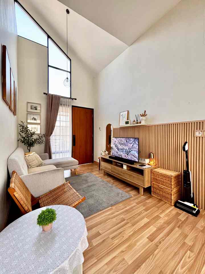A white and wood-tone living room featuring a sofa, TV stand, and carpet, creating a warm and cozy atmosphere with modern natural style