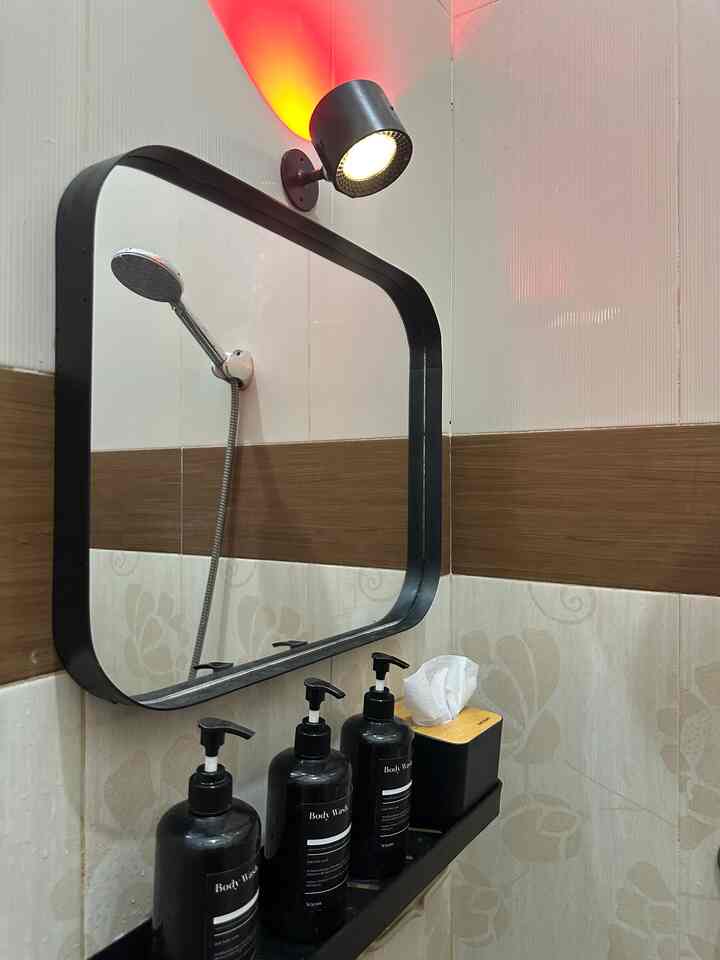 Bathroom featuring black accents and wood tones, with three pump bottles and sleek wall lighting creating a clean atmosphere