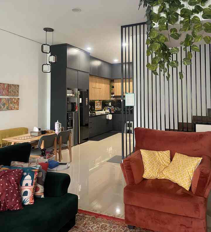 Modern open space living room and kitchen featuring green sofa, brown armchair, and wooden dining table