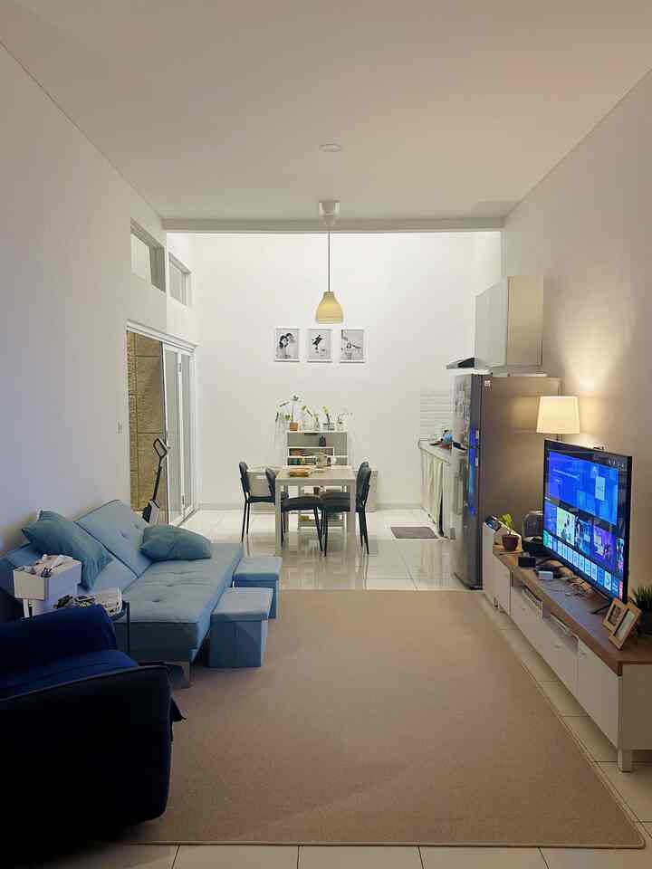 Modern living and dining area for two featuring white walls and blue sofa with clean, open atmosphere