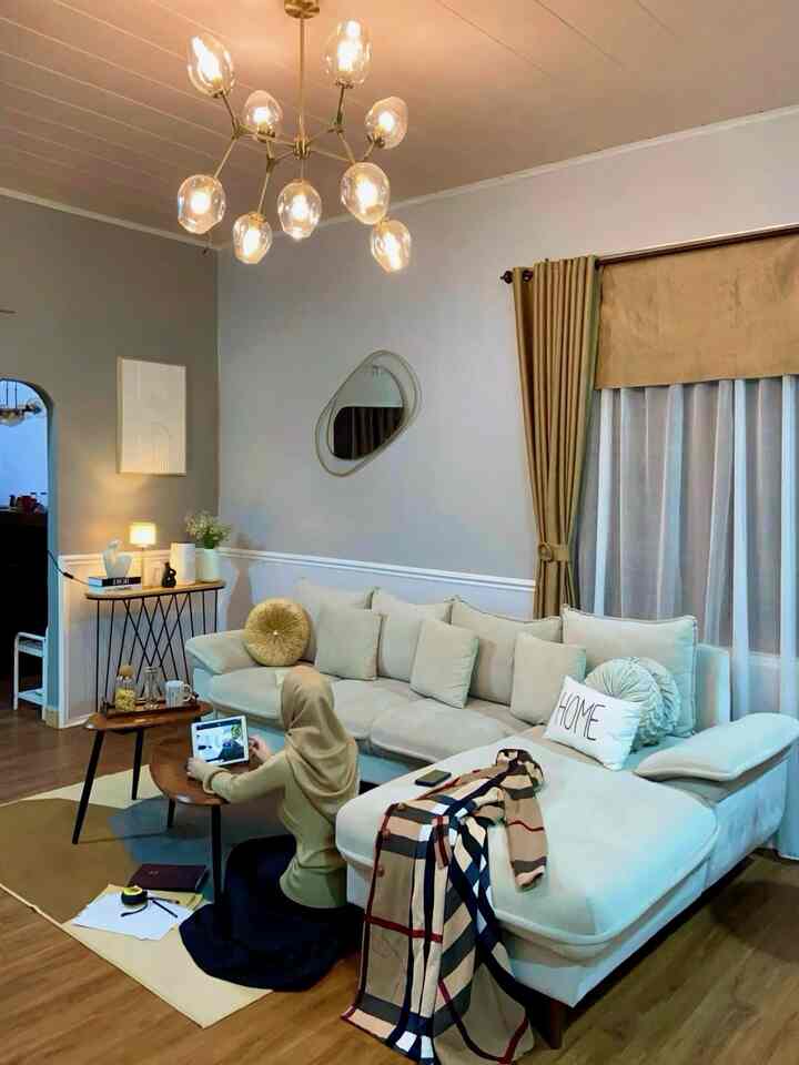 A cozy living room with soft blue walls and brown flooring featuring a large beige sectional sofa and curtains