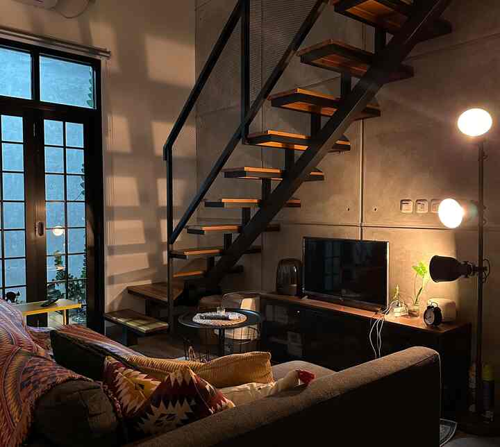 Cozy industrial living room in warm brown and cool black tones, featuring metal stairs, sofa, and floor lamp