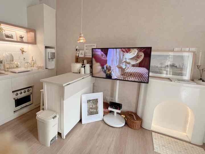 A white and natural color tone kitchen featuring a kitchen island and TV stand with a minimal atmosphere