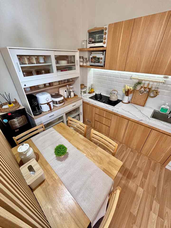 Cozy kitchen space featuring natural wood tones and ivory kitchen cabinetry with a wooden dining table and table runner