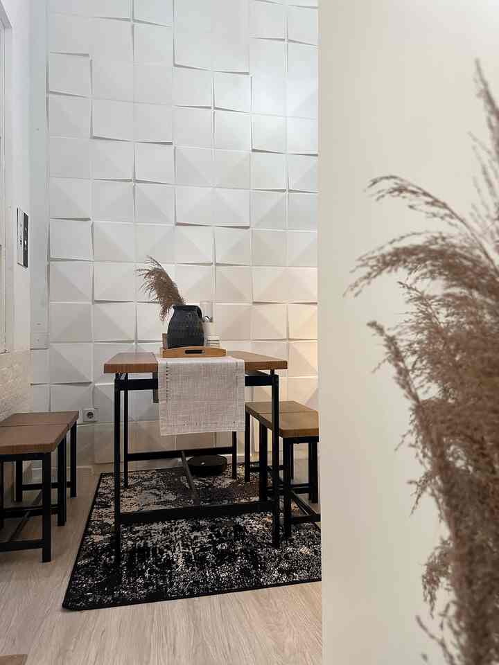 Clean dining room with white geometric wall panels, natural brown wood dining table and table runner