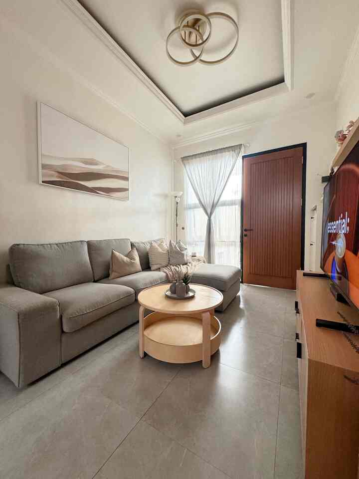 A compact living room with white and wood tones, featuring a gray sectional sofa and round coffee table in a minimal modern setting