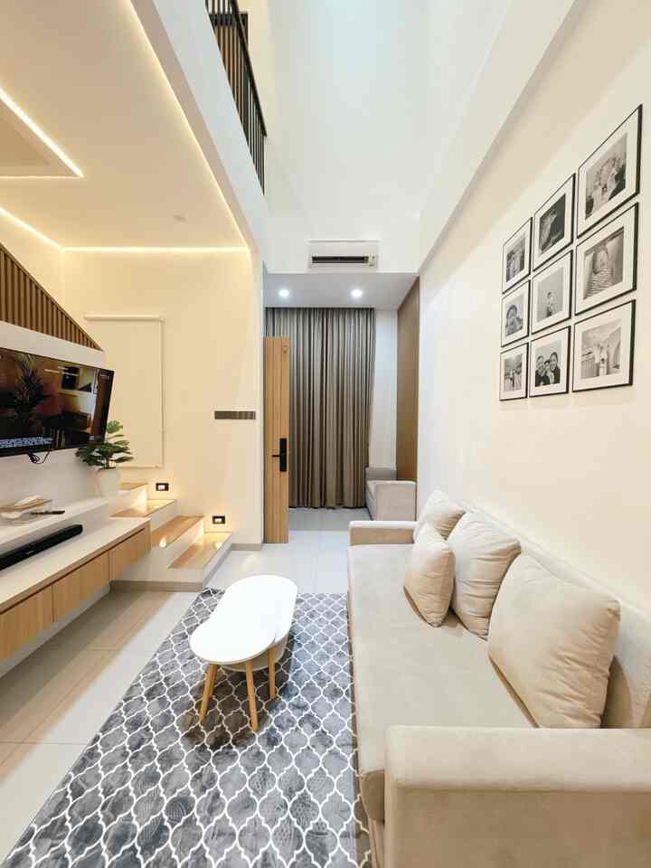 Modern living room in white and beige tones featuring a beige sofa, patterned carpet, and coffee table in a clean layout