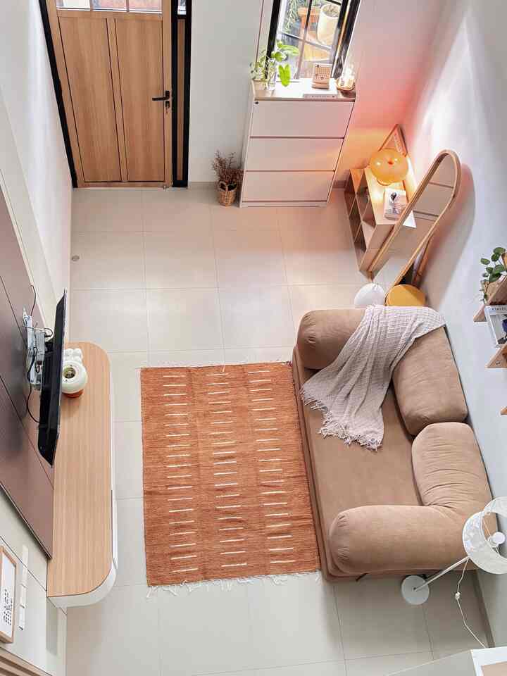 Natural tone compact living room featuring beige sofa bed, orange carpet, and a large oval standing mirror with a simple cozy atmosphere