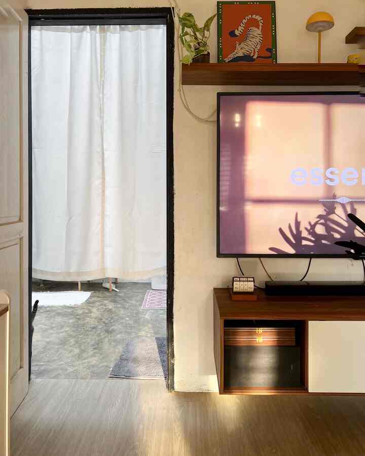 White curtain and brown floor create a warm living room space featuring a TV stand and decorative items