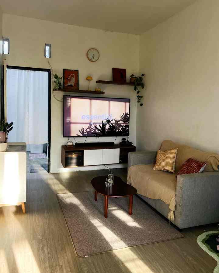 Modern living room with white walls and natural wood flooring, featuring a gray sofa and wooden coffee table for a cozy atmosphere