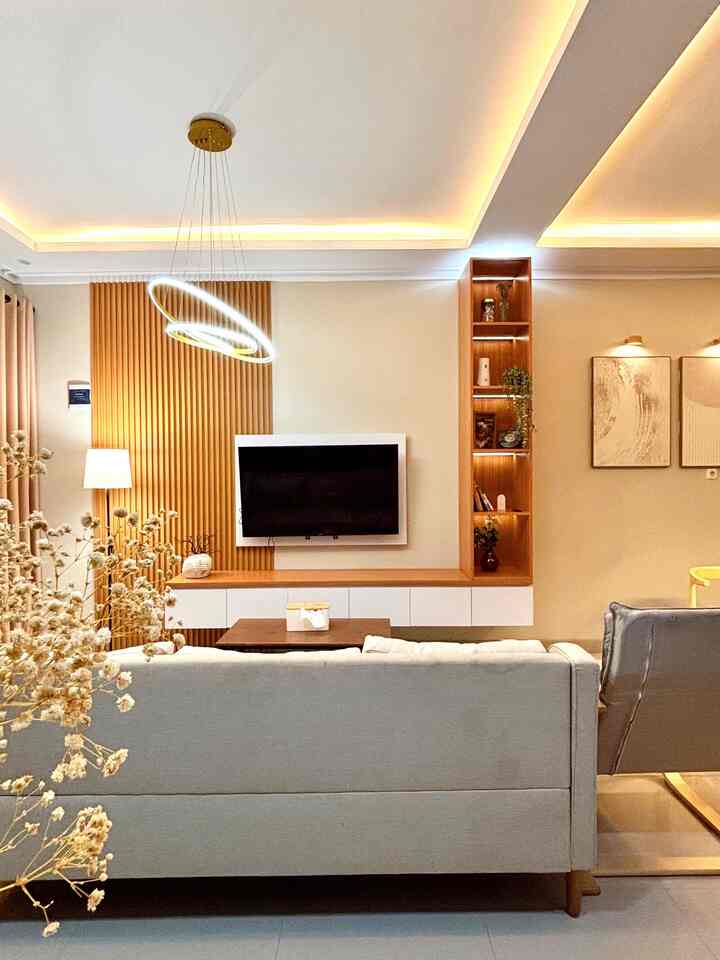 A long and narrow living room featuring white and wood tones, minimalist sofa, and pendant lighting creating a modern, cozy atmosphere.