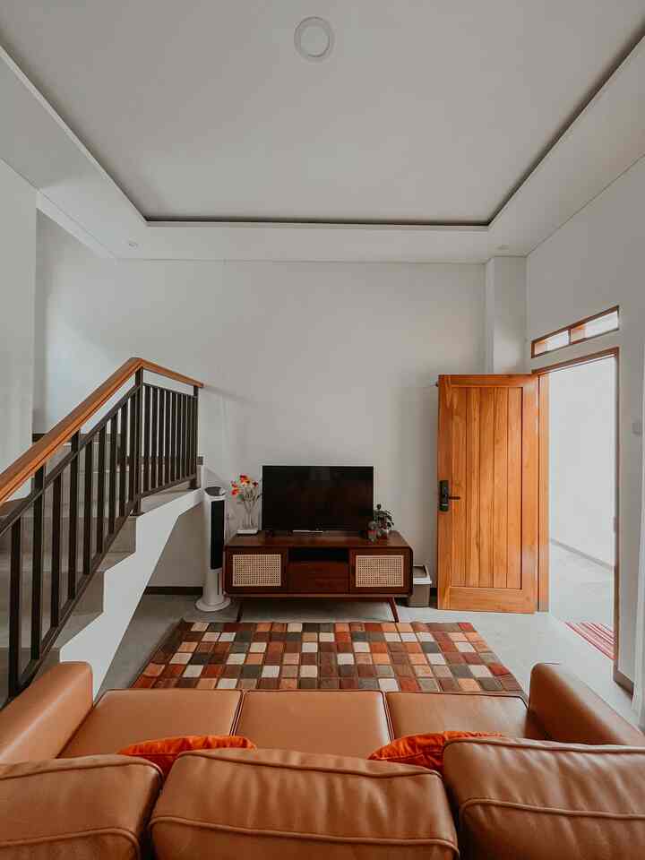 Natural style living room with white walls and ceiling featuring camel brown sofa and wood tone furniture