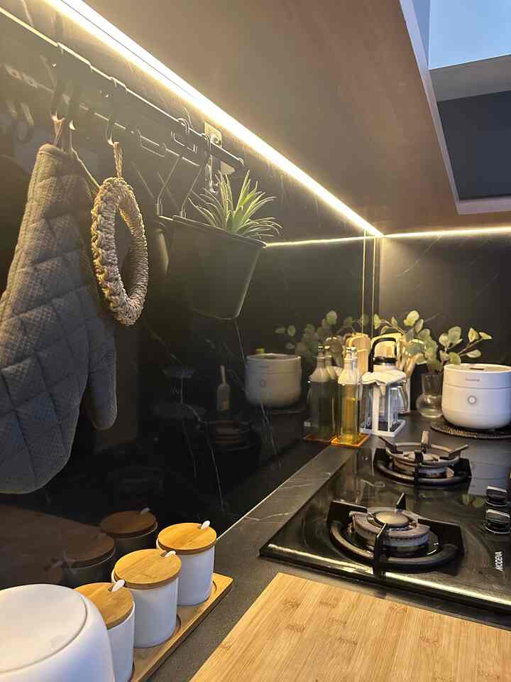 Modern kitchen in black and natural tones featuring organized kitchen utensils and LED lighting under cabinets