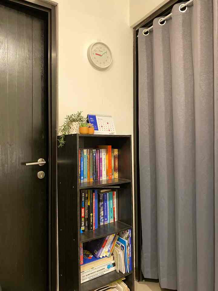 Gray curtain and dark door with a bookshelf arranged in a medium-sized entrance area