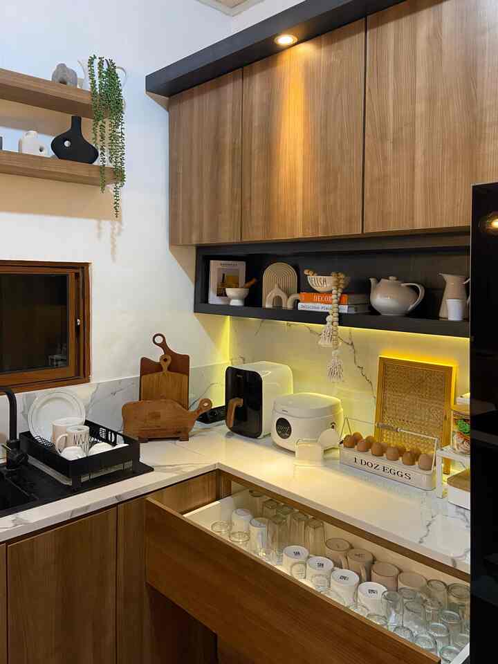 Small kitchen space featuring wood tones and white surfaces, with organized storage and warm lighting creating a cozy atmosphere