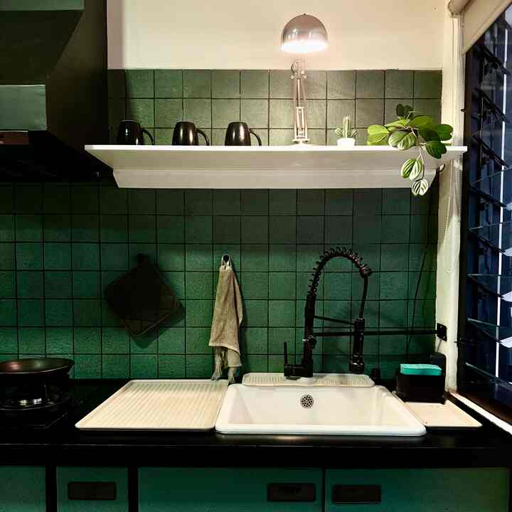 Modern kitchen space with green tiled wall and white sink