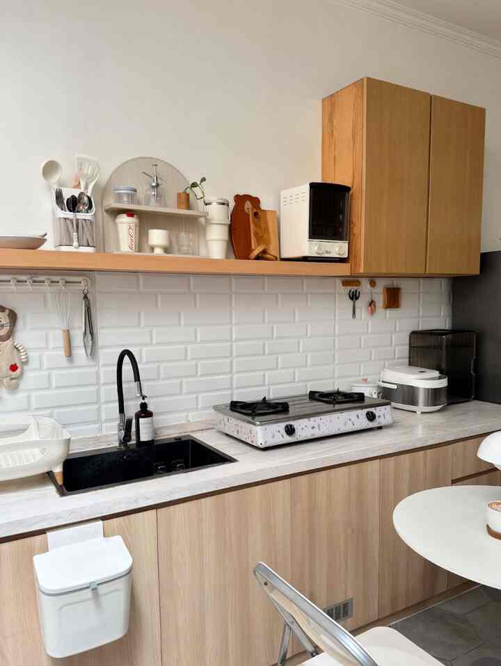Modern kitchen with natural wood tones and white tiled backsplash, featuring smart storage ideas in a clean space