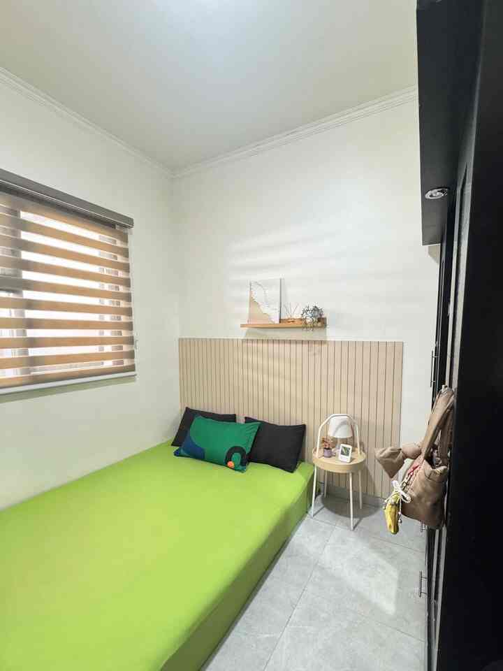 Bright white walls and beige headboard in a compact bedroom with green bedding for a fresh, airy feel