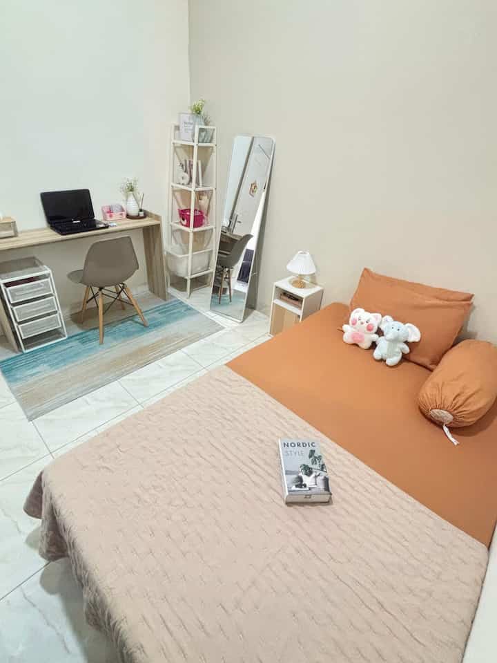 Beige and brown toned bedroom space featuring bed and desk with a cozy, minimal atmosphere