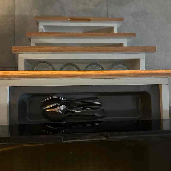 White and brown toned kitchen drawers featuring neatly arranged spoons and glass containers for an organized storage space