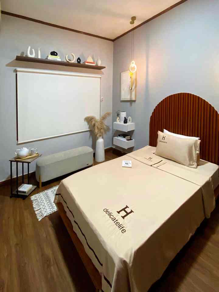 Cozy bedroom in beige and wood tones featuring a simple bed, wall-mounted shelves, roller blind, and pendant lighting