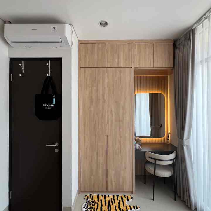 Beige wood tone built-in closet and entrance area with lighting in a small, neat space