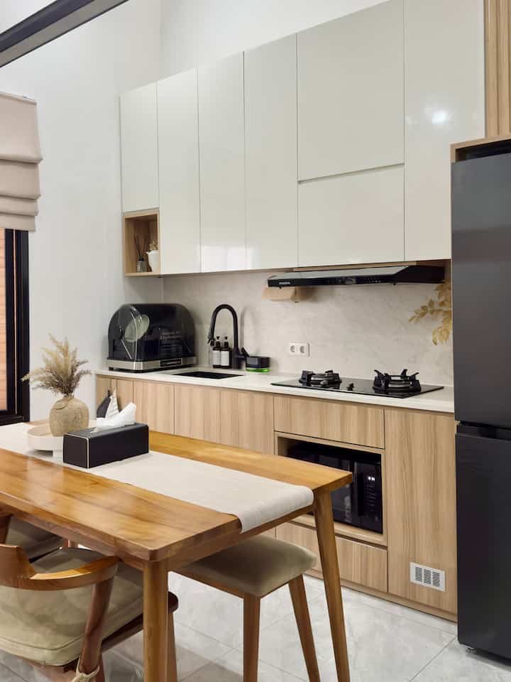 Natural brown and white toned clean kitchen space featuring wooden dining table and modern cabinetry in harmony