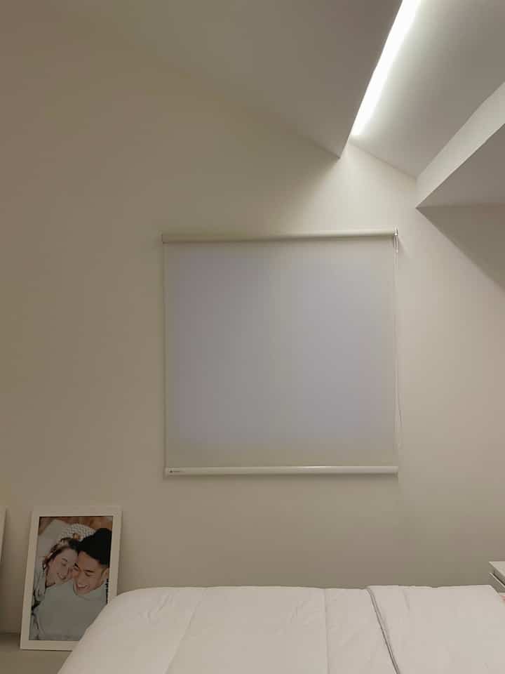 White-toned small bedroom featuring a roller blackout blind and clean bedding in a minimalistic space