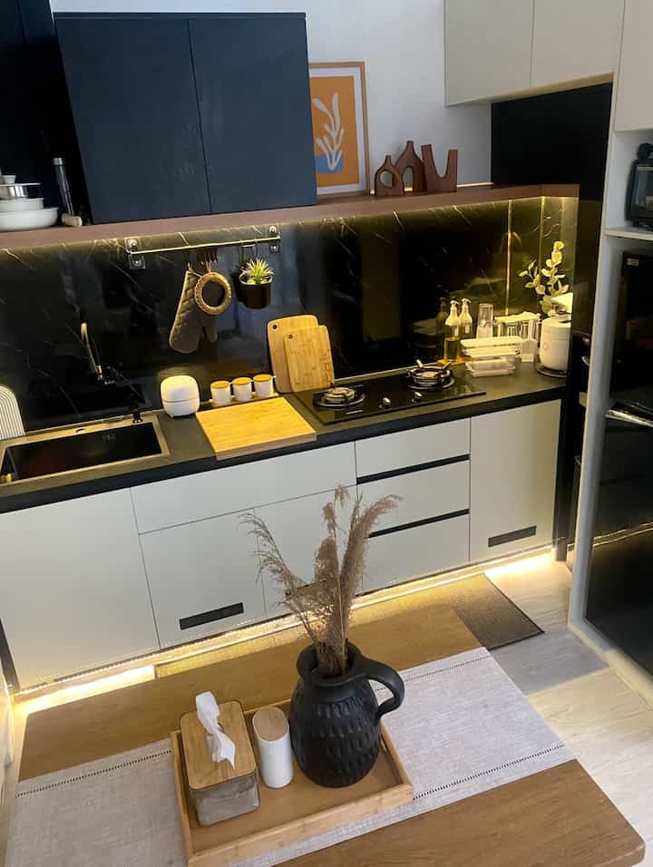L-shaped kitchen in black and natural wood tones featuring cutting boards and utensils with a modern organized atmosphere