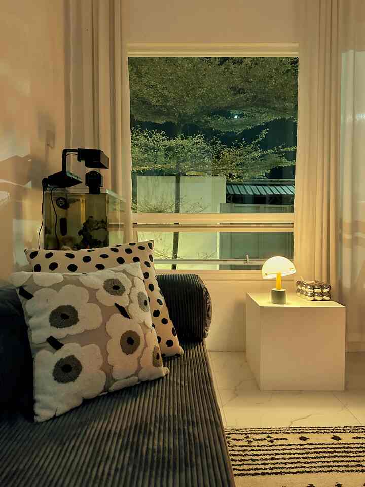 White and black toned living room featuring a corduroy sofa with cushions, a small side table with lamp, showcasing a modern interior