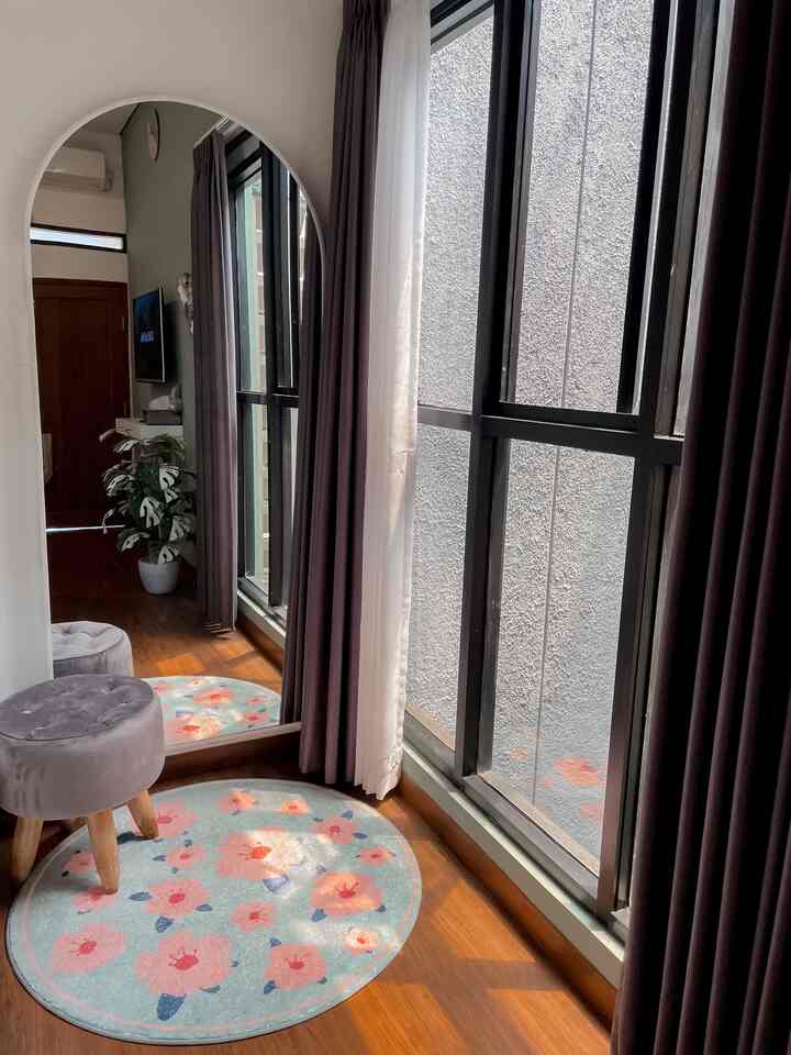 Natural-toned balcony space featuring a gray stool and floral round carpet with cozy atmosphere