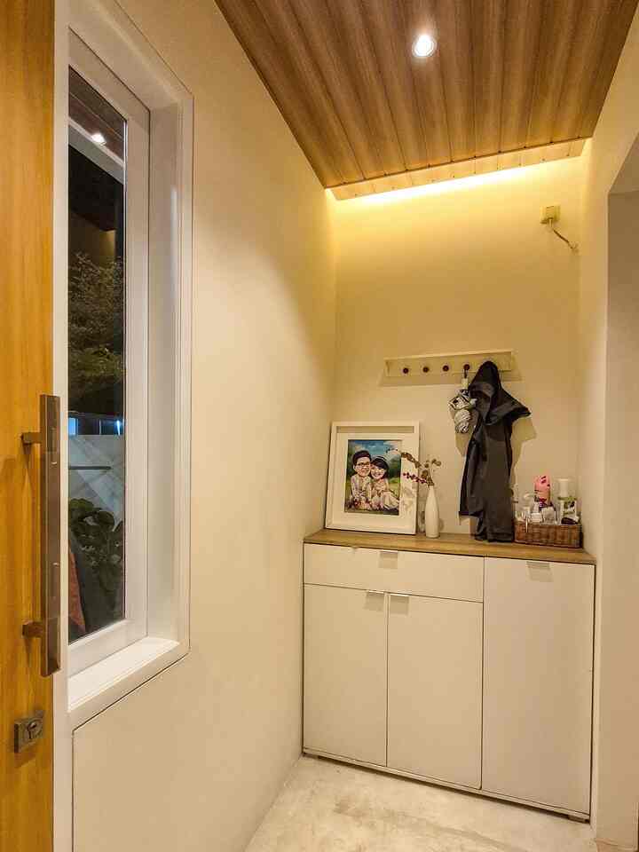 Foyer

Ruang ini merupakan foyer atau area peralihan sebelum memasuki ruang tamu. Fungsinya multifungsi sebagai tempat menyimpan sepatu sekaligus menyimpan berbagai perlengkapan seperti alat tukang, kebutuhan dapur, kamar mandi, dan perlengkapan anabul. Di bagian atas terdapat gantungan dinding untuk menggantung jaket, tas, atau payung setelah dari luar.

Untuk alasan fungsional, lantai area ini menggunakan semen ekspos karena lebih tahan terhadap kotoran dan lebih mudah dibersihkan. Sebagai aksen, plafon dipasang panel PVC motif kayu dengan dua jenis pencahayaan: tiga titik lampu spotlight 3 watt dan cove lighting di sisi plafon untuk menambah kesan hangat.

Plafon foyer ini dibuat lebih rendah dibanding ruang tamu untuk menciptakan efek transisi yang dramatis. Perbedaan tinggi plafon dan jenis flooring menambah kesan “wow” saat berpindah dari foyer menuju ruang utama melalui kongliong.

#foyerdesign #interiortransisi #rumahminimalis #semenekspos #plafonPVC #coveLighting #entrywayideas #rumahhangat #desainrumahkecil #homeentrydecor #plafondpvc #cattembok #gantungan #lemarisepatu #lantaivinyl 