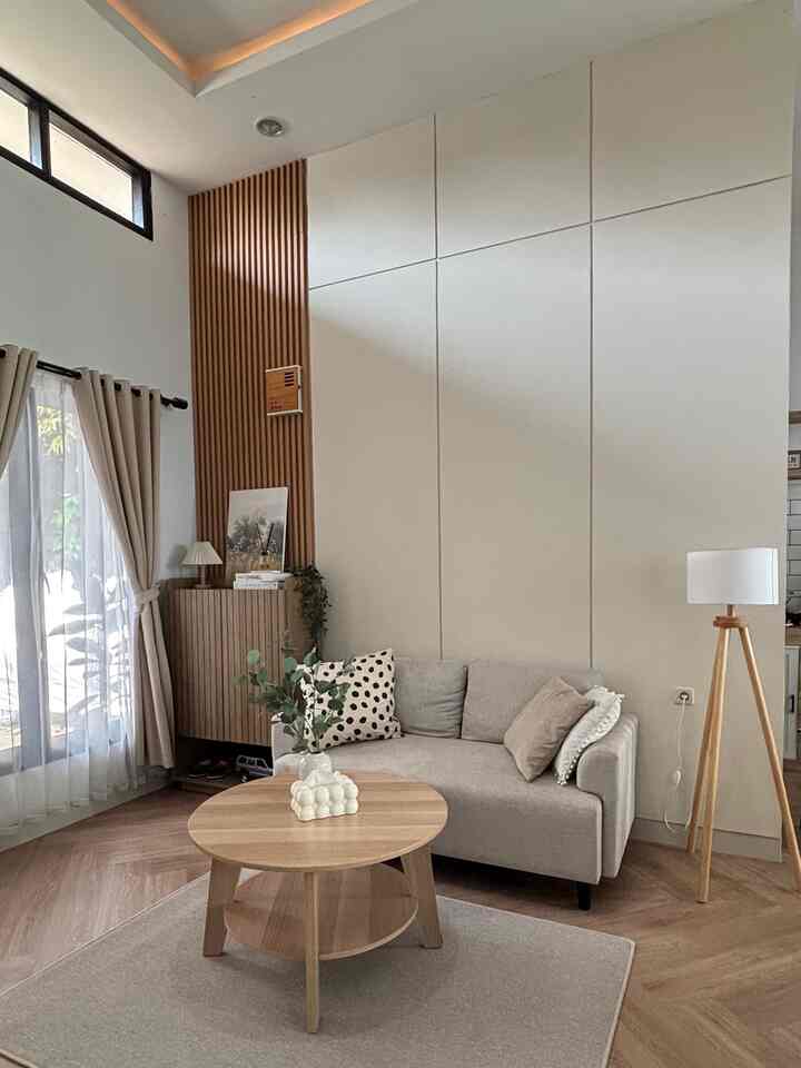 A natural beige and wood tone living room featuring a simple modern sofa and round coffee table creating a cozy atmosphere