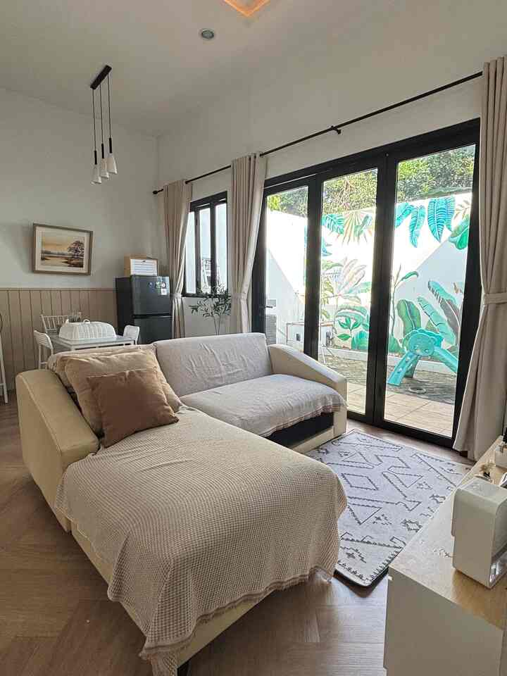 Beige and white toned living room featuring sofa, curtains, and carpet with a natural, cozy atmosphere