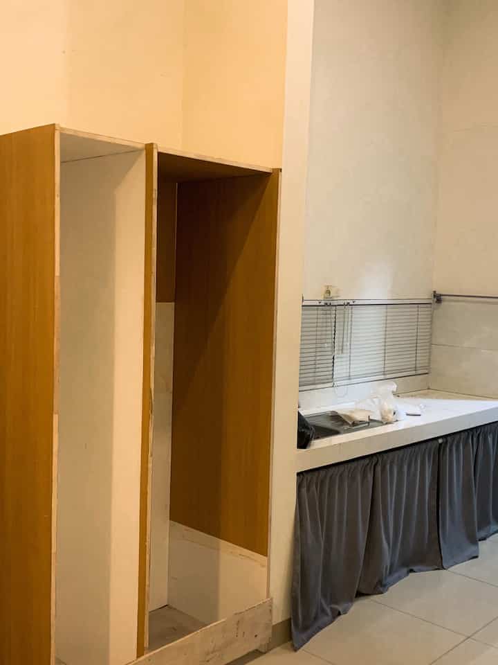 Bright natural-colored kitchen space featuring unfinished wooden cabinetry and aluminum venetian blinds with visible details