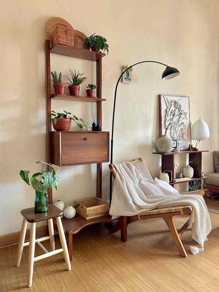 Natural toned living space featuring wood furniture, plants, and a cozy blanket draped chair creating a warm and inviting atmosphere
