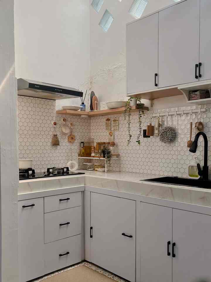White-toned kitchen space featuring hexagonal tile backsplash, wooden floating shelves, and black faucet and handles creating a modern, natural atmosphere.