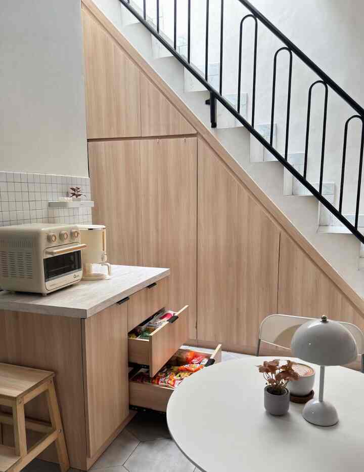 White and wood tone kitchen and dining room with sleek built-in storage under stairs in a modern setting