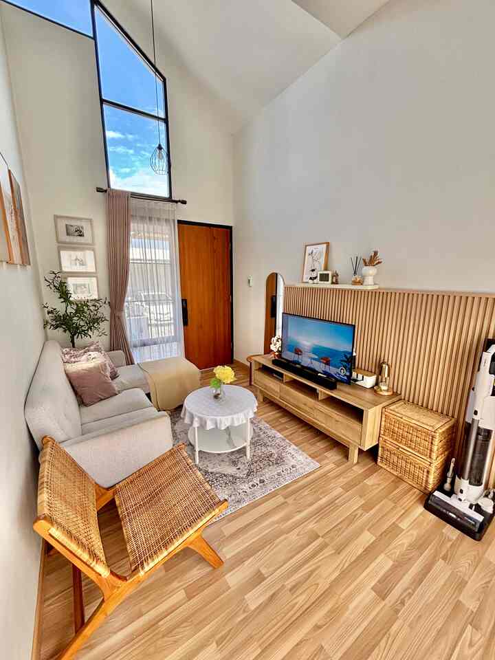 Bright natural wood tone small living room featuring beige sofa, vintage carpet, rattan chair, with a cozy and airy atmosphere