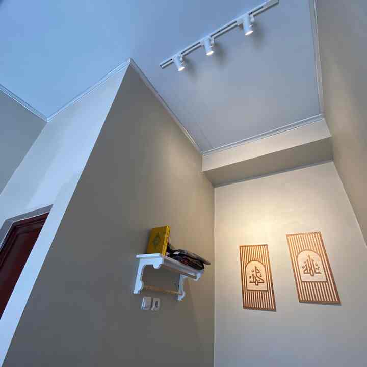 White and beige toned small room featuring wall sconces and a decorative shelf with a simple ambiance