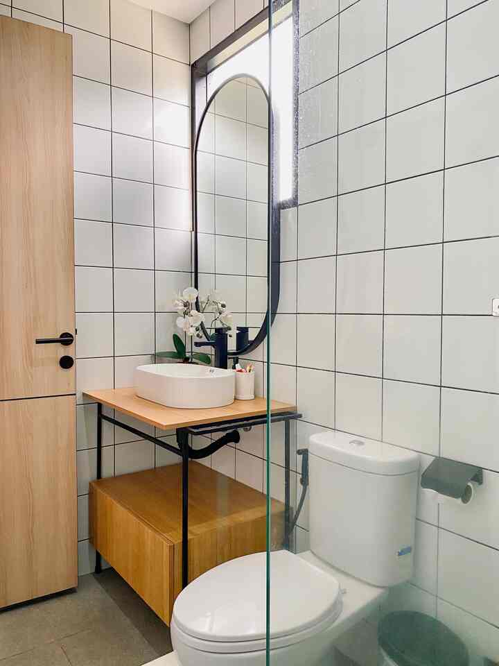 White tiled, narrow and long bathroom featuring brown wood furniture and modern fixtures