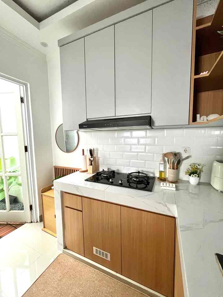 Compact kitchen space in white and wood tones featuring a built-in gas stove and round mirror, with clean and natural decor
