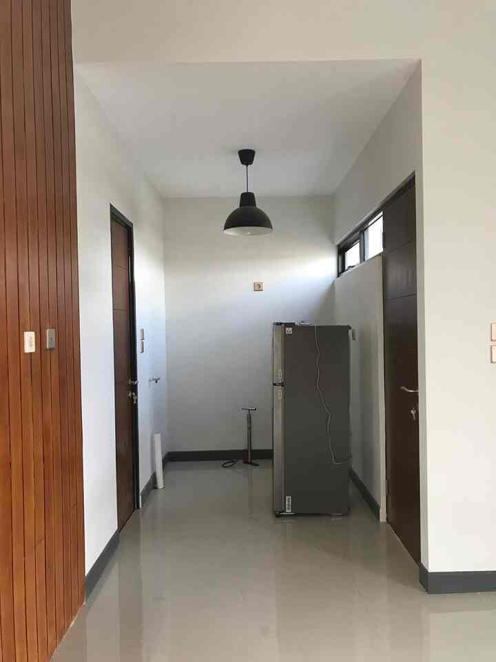 White-walled and floored residential hallway featuring a black pendant lamp with minimal furnishings