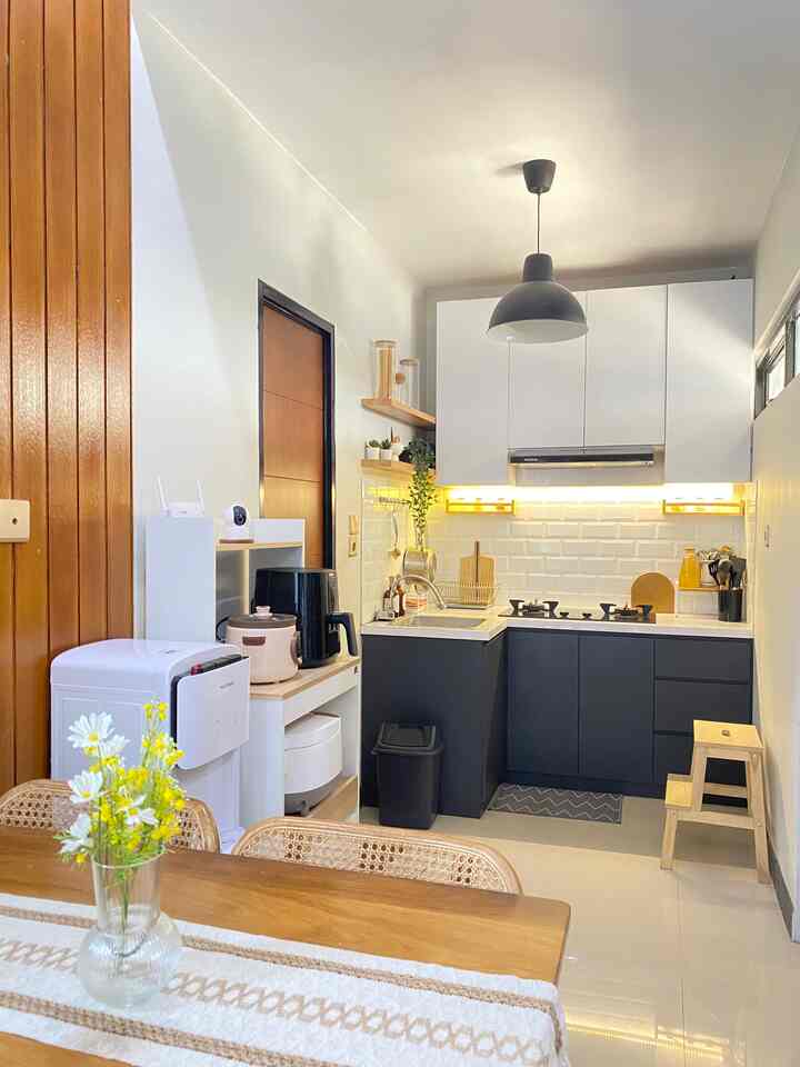 A natural-tone kitchen space with a white and black color scheme, featuring a wooden dining table and a small stool, creating a cozy and clean kitchen environment
