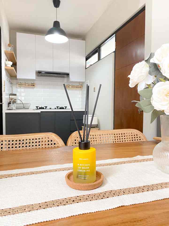 White and brown toned kitchen and dining area featuring a yellow reed diffuser and floral decorations for a warm, cozy atmosphere