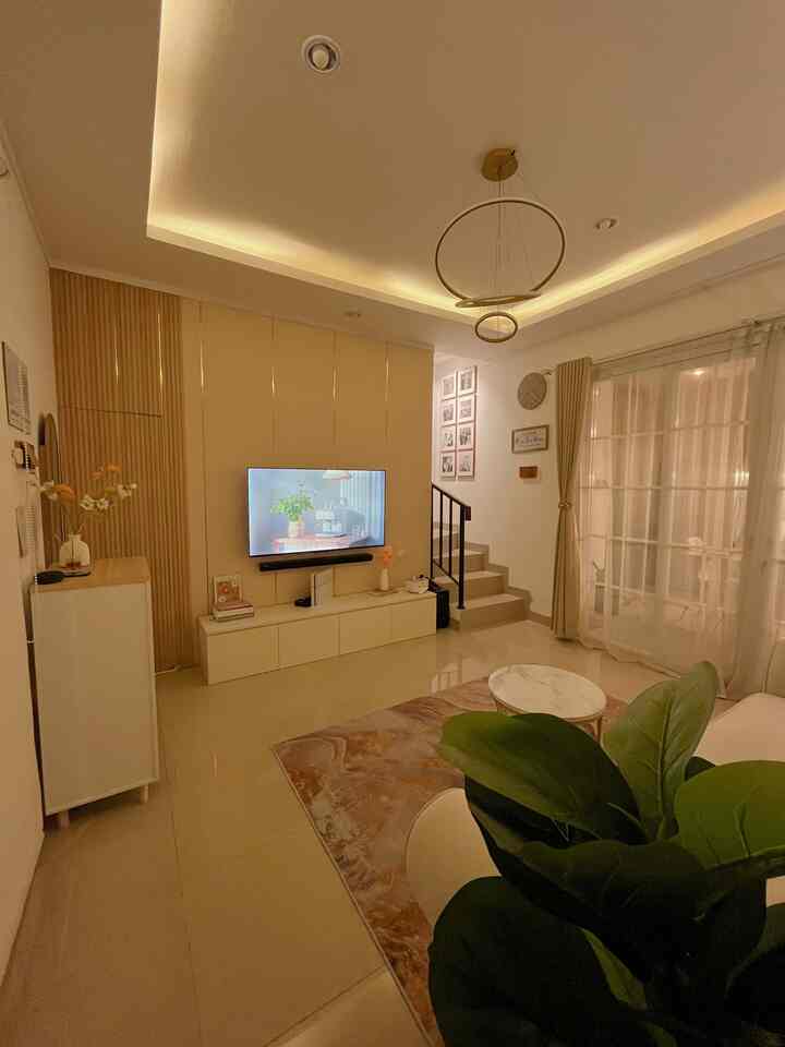 A beige natural-tone living room featuring a central TV stand and carpet, creating a cozy atmosphere