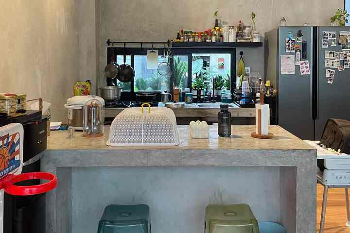 Natural tone concrete kitchen with countertop by window and various kitchen utensils arranged, practical space