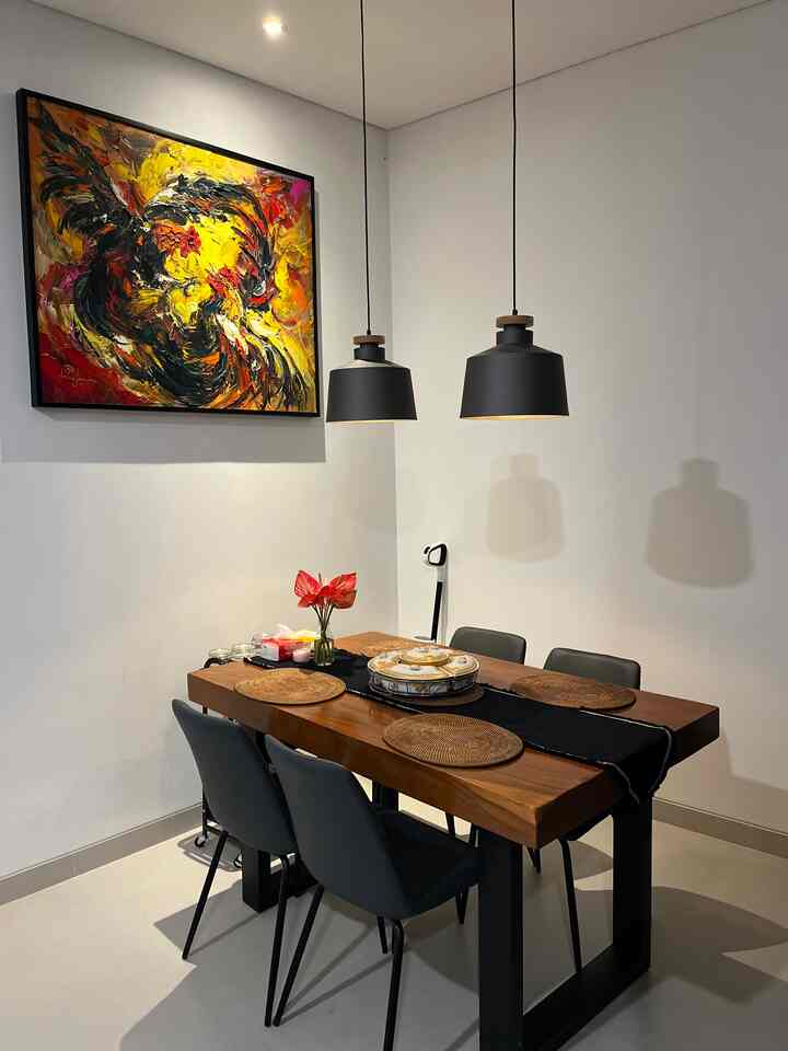Modern dining room with brown wooden table and black dining chairs, featuring bold yellow abstract wall art and black pendant lights