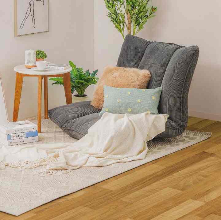 Bright white and natural wood-toned small room featuring a gray floor chair and round coffee table in a cozy reading nook
