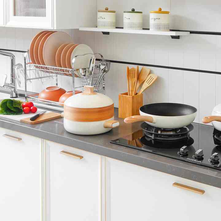 Clean kitchen in white and wood tones featuring organized cooking utensils and dishware on countertop